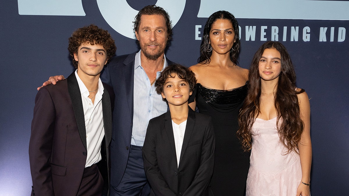 Matthew McConaughey dengan blazer biru berpose bersama istrinya Camilla dalam gaun hitam dan ketiga anak mereka Levi, Livingston, dan Vida