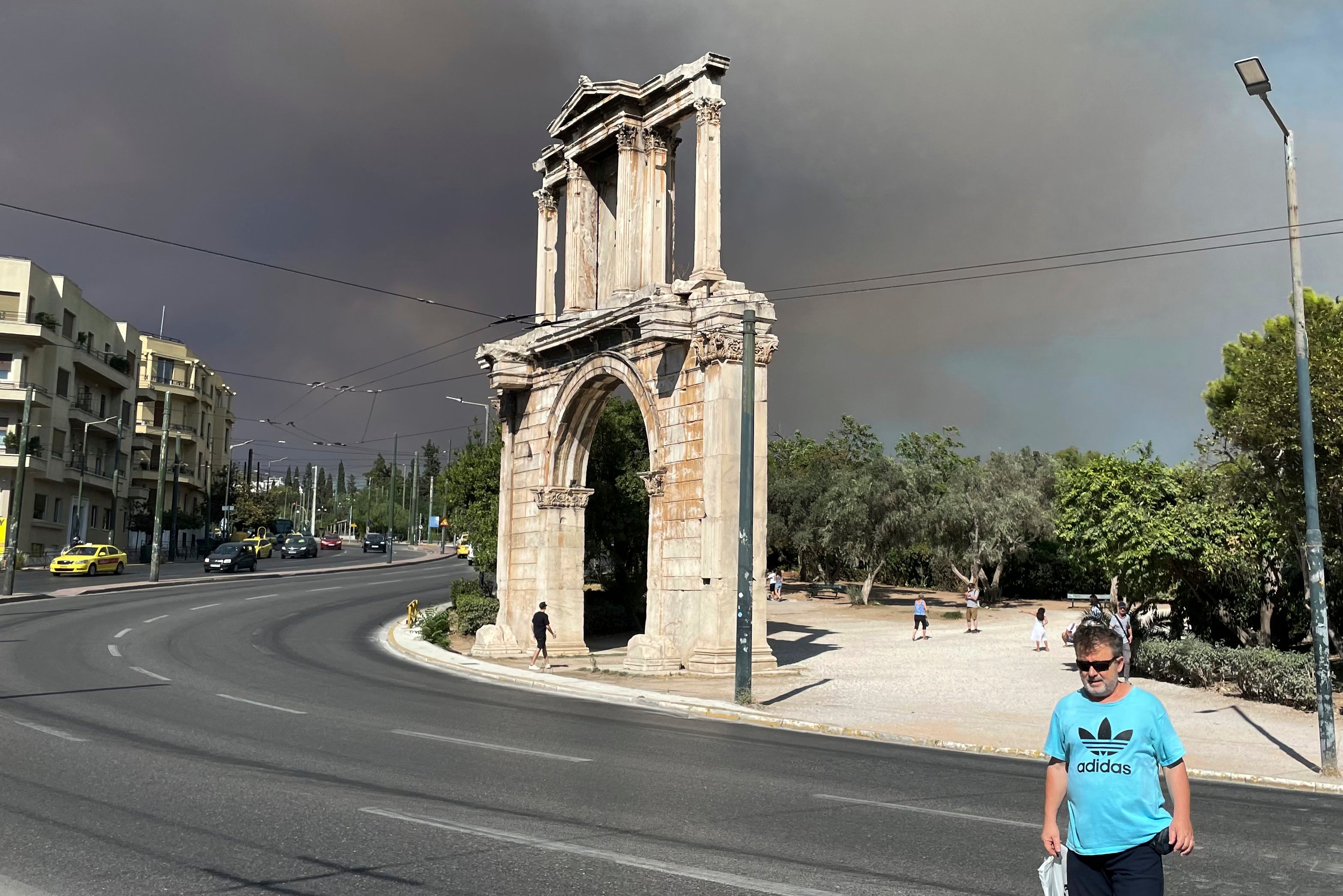 Asap kebakaran hutan terlihat di atas Hadrian's Arch di pusat Athena, Minggu, 11 Agustus 2024.