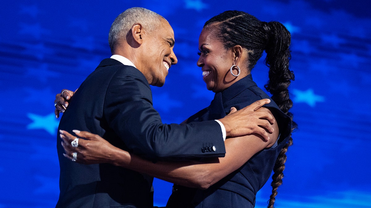 Barack Obama menyapa istrinya Michelle Obama di atas panggung dengan gaun biru tua dan mereka berpelukan