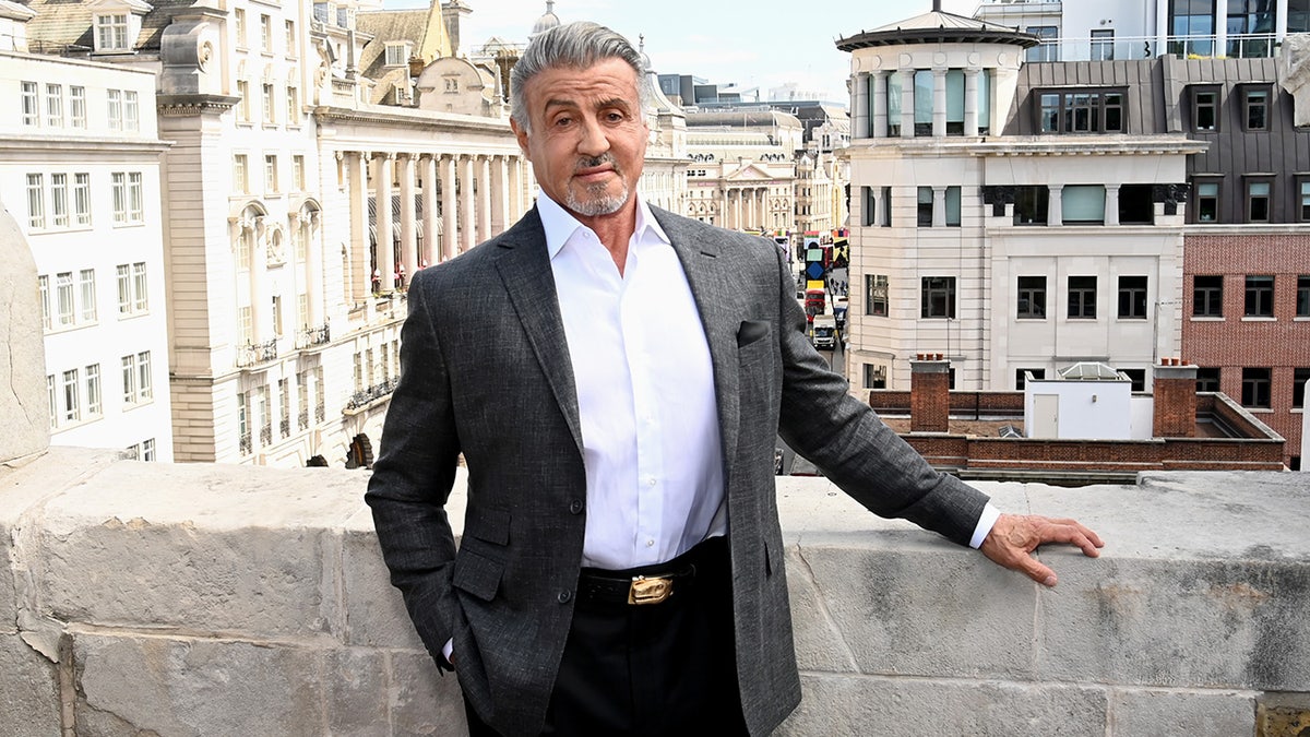 Sylvester Stallone berpose untuk foto dengan setelan gelap dan celana hitam