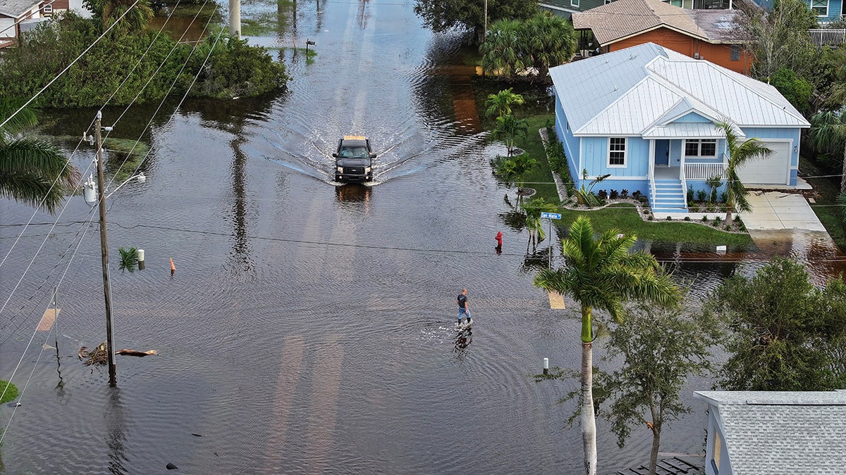 Dalam pandangan udara ini, seorang pria berjalan melewati air banjir yang menggenangi suatu daerah setelah Badai Milton menghantam daratan.