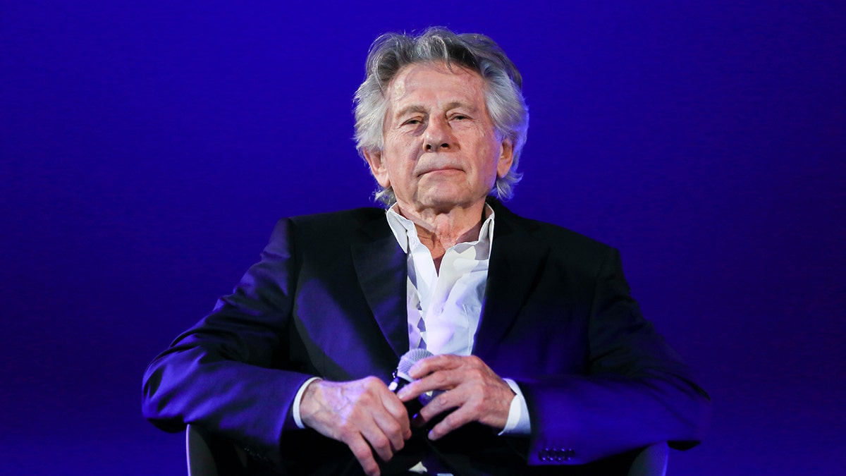 Sutradara Roman Polanski mengenakan kemeja putih dan blazer hitam.