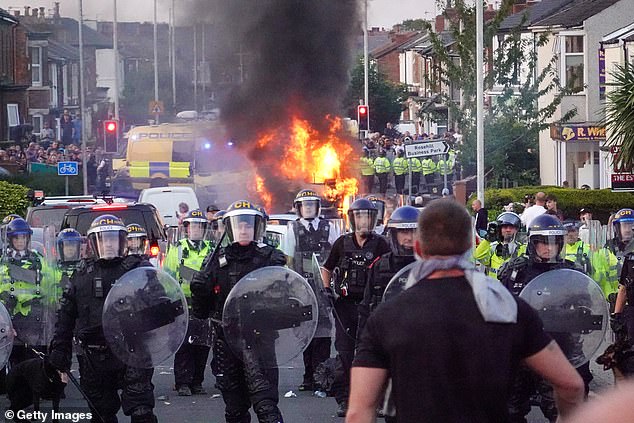 Disinformasi yang memicu kerusuhan musim panas 'diserang secara berlebihan' oleh bot asing, kata kepala kepolisian kontra-teror Inggris. Gambar: Polisi anti huru hara memblokir pengunjuk rasa di dekat kendaraan polisi yang terbakar saat kerusuhan meletus di Southport