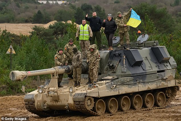 Anggota baru Ukraina dan pelatih Angkatan Bersenjata Inggris mereka berpose untuk foto sistem artileri self-propelled AS90 di fasilitas militer di Inggris selatan pada 23 Februari 2023.