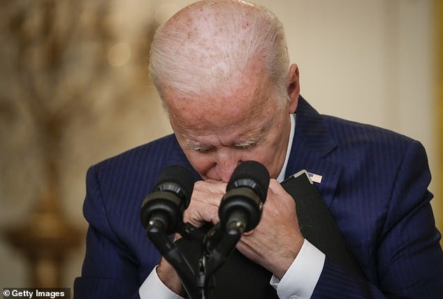 Presiden AS Joe Biden berhenti sejenak dan memegang mapnya sambil mendengarkan pertanyaan dari seorang reporter