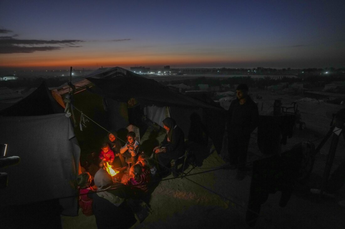 Reda Abu Zarada, 50, pengungsi dari Jabalia, Gaza utara, duduk di dekat api bersama cucu-cucunya di kamp tepi pantai di Khan Younis, Jalur Gaza, Kamis, 19 Desember 2024.