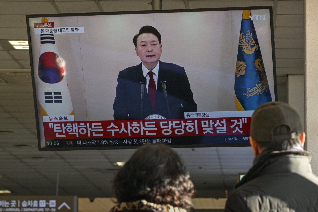 Orang-orang menonton layar yang menunjukkan Presiden Korea Selatan Yoon Suk-yeol berbicara dalam pidato yang disiarkan televisi di terminal bus di Seoul pada 12 Desember 2024. 