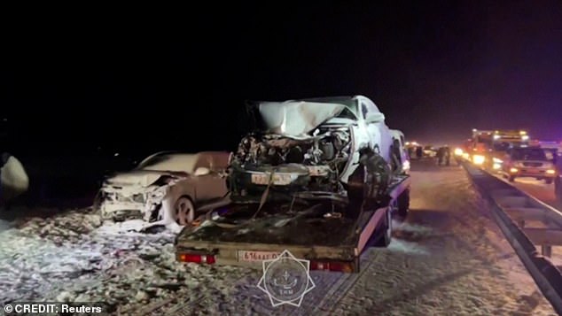Gambar menunjukkan pihak berwenang Kazakh sedang menarik mobil yang rusak