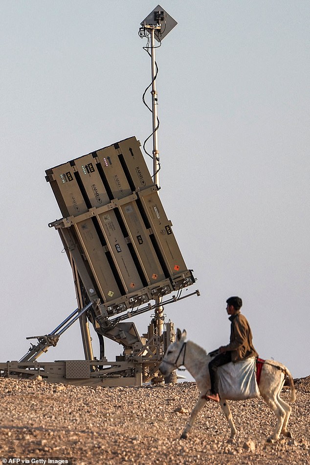 Seorang anak laki-laki mengendarai keledai di dekat salah satu baterai sistem pertahanan rudal Iron Dome Israel