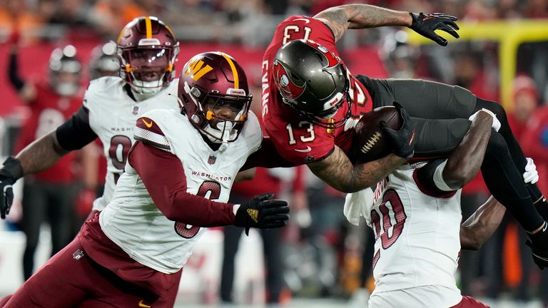 Penerima lebar Tampa Bay Buccaneers Mike Evans (13) menangani keselamatan Washington Chiefs Quan Martin, kanan bawah, dan gelandang Dante Fowler Jr., kiri depan, selama paruh kedua pertandingan sepak bola playoff dengan NFL Wild Cards di Tampa, Florida. , Minggu, 12 Januari 2025. (Foto AP/Chris O'Meara)