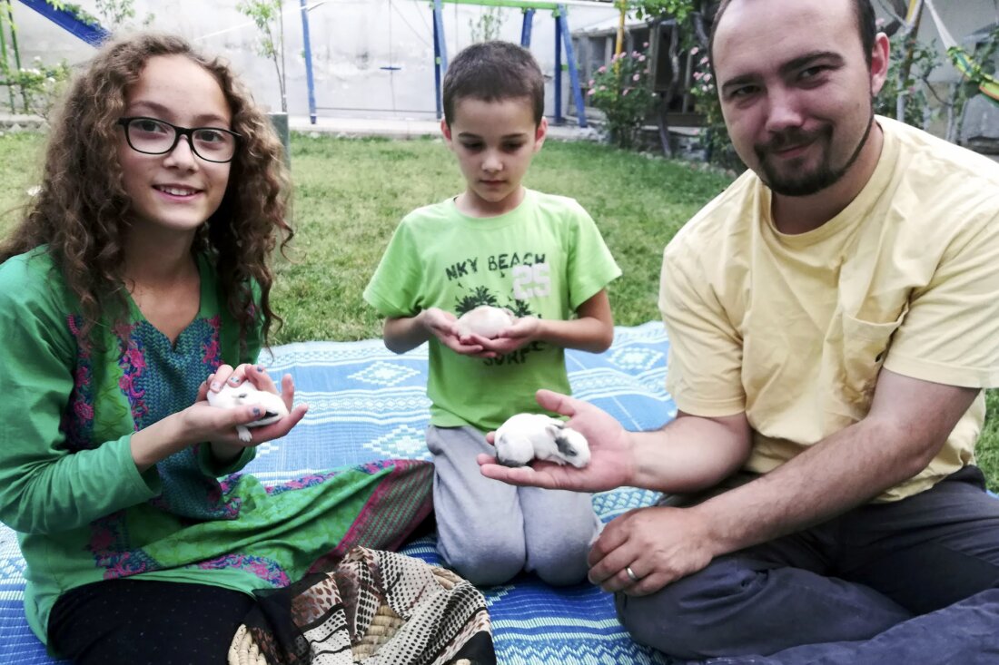 Foto keluarga ini memperlihatkan Ryan Corbett sedang menangkap kelinci bersama putrinya Miriam dan putranya Caleb di Kabul, Afghanistan pada tahun 2020. (Oleh Anna Corbett AP)