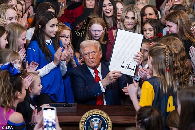 Presiden AS Donald Trump (c) Dikelilingi dengan atlet wanita muda, menandatangani perintah eksekutif untuk melarang atlet transgender dari ruang timur Gedung Putih di Washington