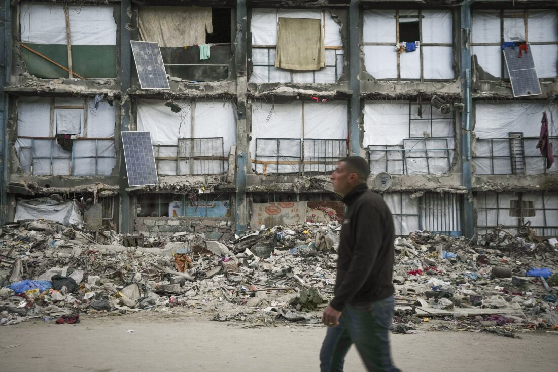 Seseorang melintasi sebuah rumah yang sebagian berdiri, tetapi lembaran yang bekerja sebagai dinding sementara dan panel surya sebagian bekerja di area angin tentara Israel dan serangan darat pada hari Rabu di Gaza City.